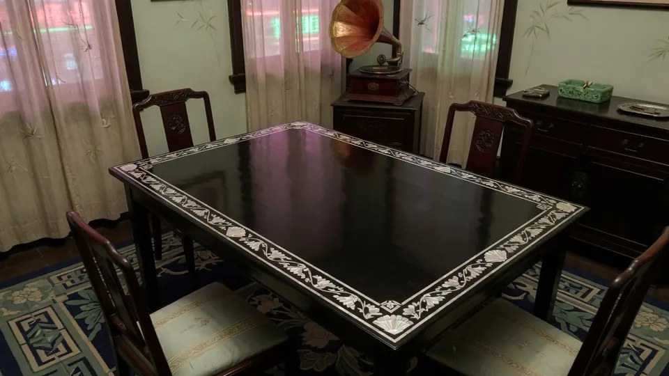 A black lacquer card table with inlaid edges, beside a gramophone, in a 1920s parlor.